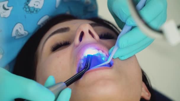 Чоловік-стоматолог в медичних рукавичках працює з пацієнткою в стоматологічному кабінеті. Стоматолог і пацієнт в клінічному кабінеті. Концепція догляду за зубами — стокове відео