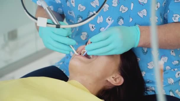 Un dentista con guantes médicos trabaja con una paciente en un consultorio dental. Concepto de salud y medicina. Odontología — Vídeo de stock