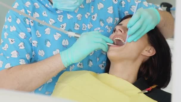 A man dentist in a medical gloves works with a patient girl in a dental office. Toothcare concept. Dentistry — Stock Video
