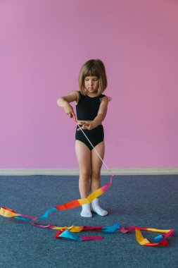 Tender beautiful girl is engaged in gymnastics on a background of a pink wall