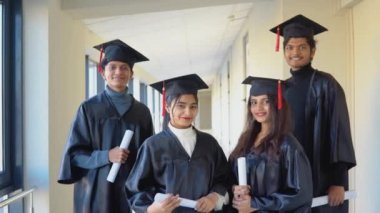 Indian university graduates stand in front of the camera in masters hats and black robes