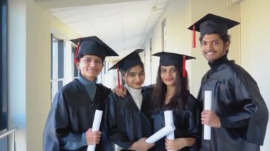 Indian university graduates stand in front of the camera in masters hats and black robes