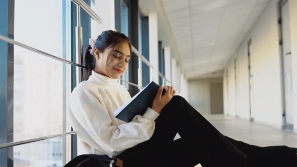 Estudiante india sentada en el suelo con un libro en la universidad o la universidad. Nueva instalación educativa moderna totalmente funcional. Concepto de educación en línea — Vídeos de Stock