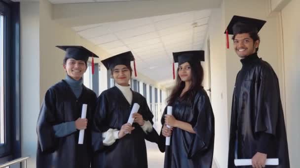 Indian university graduates stand in front of the camera in masters hats and black robes — ストック動画