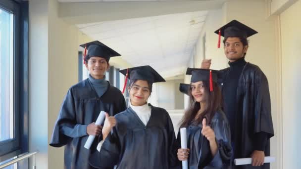 A group of indian students with diplomas stand in the university building