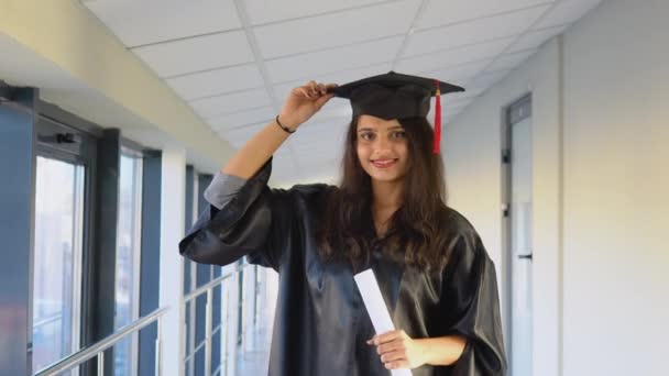 맨틀에서 졸업 한 인도 여성은 손에 졸업장을 쥐고 미소를 지으며 서 있다. 의대를 졸업하고 졸업장을 받다 — 비디오