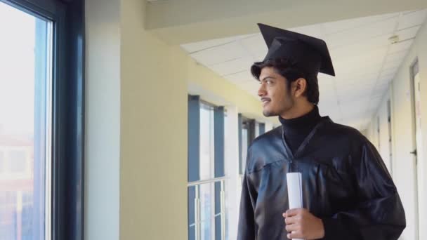 Graduada india en manto tiene un diploma en sus manos y sonríe. Especialista joven — Vídeo de stock