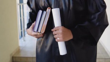 Indian graduate in mantle stands with a diploma in her hands. Closeup