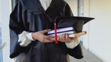 Indian female graduate in mantle stands with a books in her hands. Closeup