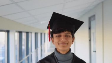 Portrait of a indian graduate in black gown and wearing masters hat in university. Young specialist