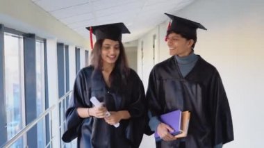 Two indian graduates walking down the corridor of the university. Education concept