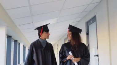 Two indian graduates walking down the corridor of the university. Education concept