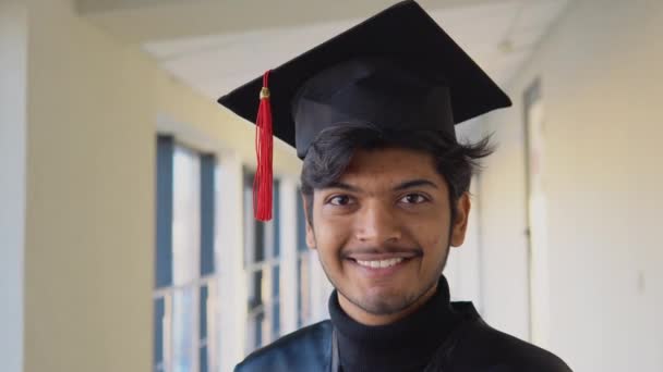 Retrato de un indio graduado en vestido negro y con sombrero de máster en la universidad. Especialista joven — Vídeo de stock