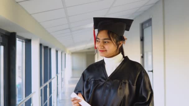 Indian female graduate in mantle stands with a diploma in her hands and smiles. A graduate of a medical university with a diploma — ストック動画