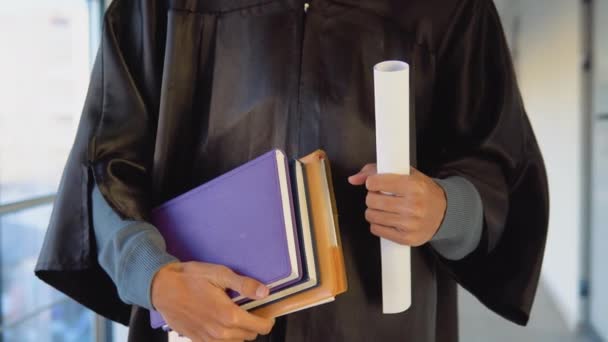 Hombre indio graduado en manto está parado con un diploma en sus manos. Primer plano. — Vídeos de Stock