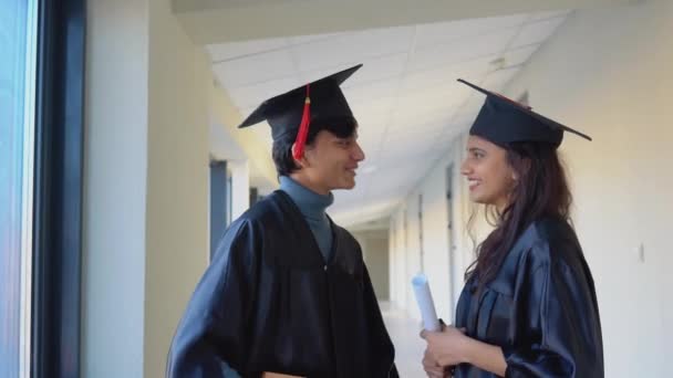 Two indian students graduates with diplomas communicate in the university building — ストック動画