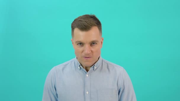 Caucasian middle-aged man in a blue shirt expresses anger, rage, aggressive shouting. Office worker standing in front of a bright blue background — Stockvideo