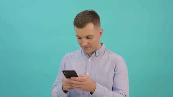 Caucásico hombre de mediana edad en una camisa azul se corresponde en un teléfono inteligente. Increíble promo — Vídeos de Stock
