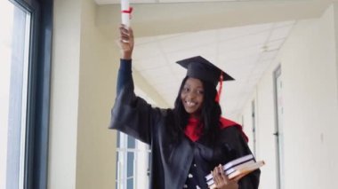 Siyahi önlüklü ve üniversitede yüksek lisans şapkalı Afrikalı kadın mezun. Önemli bir olay. Genç bir uzman. Diplomalı bir ekonomi üniversitesi mezunu.