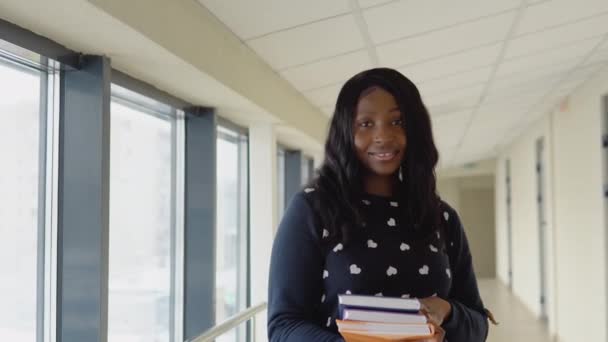 Afroamerikanische Studentin mit einem Buch an der Universität. Neue moderne, voll funktionsfähige Bildungseinrichtung. Konzept der Online-Bildung — Stockvideo