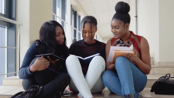 Un grupo de estudiantes afroamericanos se sientan en el suelo con libros y una tableta en la universidad. Concepto educativo — Vídeos de Stock