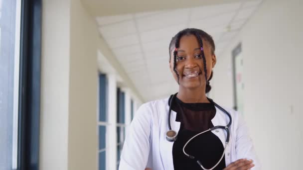 Afrikanische Ärztin oder Internistin posiert mit Stethoskop und blickt in Klinik in die Kamera — Stockvideo