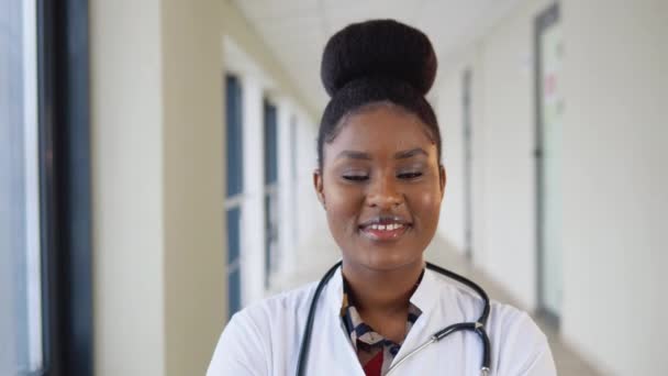 Retrato de médico afro-americano feminino ou estagiário profissional generalista posando com estetoscópio olhando para a câmera na clínica — Vídeo de Stock