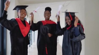 Bir grup neşeli Afro-Amerikan öğrenci diplomalarla zıplıyorlar. Üniversite eğitiminin başarısı. Bilimin Efendisi