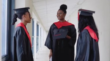 Bir grup Afrikalı Amerikalı diplomalı öğrenci üniversite binasında iletişim kuruyor. Üniversite öğreniminin başarısı