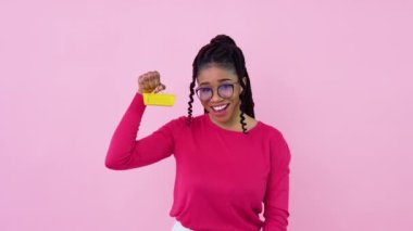 Pembe elbiseli sevimli, neşeli, Afro-Amerikalı kız elinde küçük bir oyuncak sepeti tutuyor. Genç kız ev hanımı acemi, pembe arka planda duruyor.