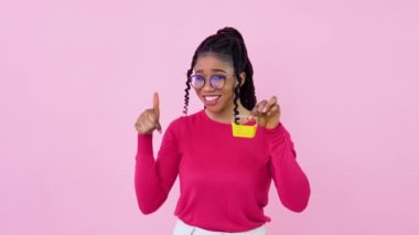 Pembe elbiseli genç Afro-Amerikan kız elinde küçük bir oyuncak sepeti tutuyor. Genç kız ev hanımı acemi, pembe arka planda duruyor.