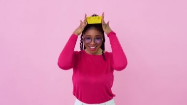 Pembe elbiseli Afro-Amerikalı kız elinde küçük bir oyuncak sepeti tutuyor. Genç kız ev hanımı acemi, pembe arka planda duruyor.