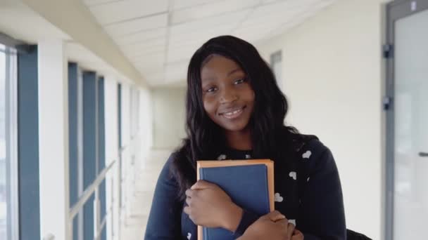 Jovem estudante africana com livros em uma biblioteca moderna — Vídeo de Stock