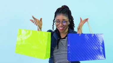 Mavi elbiseli Afro-Amerikalı kız elinde dolma kalemle plastik poşetler tutuyor. Açık mavi arka planda duran genç kız