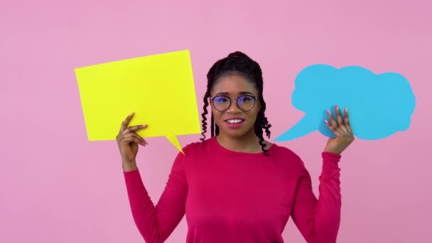 Linda chica afroamericana joven en ropa rosa se levanta con carteles de expresión sobre un fondo rosa sólido. Un lugar para consignas publicitarias — Vídeos de Stock