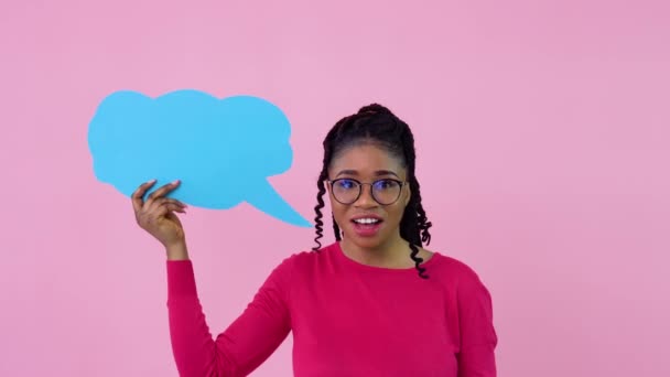 ピンクの服を着たアフリカ系アメリカ人の女の子は、しっかりとしたピンクの背景で表現するポスターで立っています。広告スローガンのための場所 — ストック動画