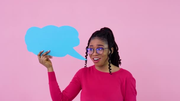 귀엽고 젊은 아프리카 계 미국인 소녀가 딱딱 한 분 홍색 배경에 표현을 위한 포스터를 들고 서 있습니다. 광고 슬로건 이 있는 곳 — 비디오