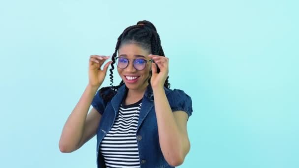 Χαριτωμένη χαρούμενη νεαρή Αφρο-Αμερικανίδα με μπλε ρούχα ποζάρει και χορεύει σε ένα φωτογραφείο. Έφηβη κοπέλα στέκεται σε ένα συμπαγές γαλάζιο φόντο — Αρχείο Βίντεο