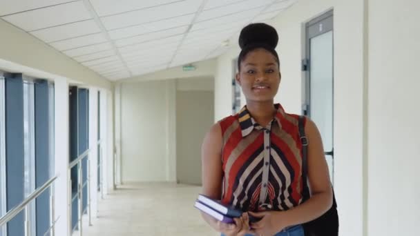 Joven estudiante africana con libros en una biblioteca moderna — Vídeos de Stock