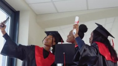 Bir grup Afrikalı Amerikalı diplomalı öğrenci üniversite binasında selfie çekiyor. Dünyanın dört bir yanındaki üniversiteler arasında öğrenci değişim programı