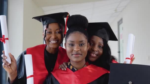 Le laureate afroamericane stanno davanti alla telecamera con cappelli da maestro e vesti nere. Programma di scambio di studenti tra università di tutto il mondo — Video Stock