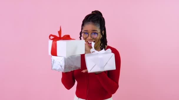 Linda chica afroamericana joven sosteniendo tres cajas de regalo. Chica adolescente en ropa roja sostiene cajas blancas con cintas rojas y blancas. Regalo de cumpleaños — Vídeos de Stock