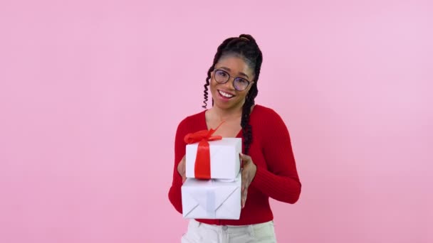 젊은 아프리카 계 미국인 아가씨가 선물 상자 두 개를 들고 있어. 빨간 옷을 입은 십 대 소녀는 빨간색 과 흰색 리본이 달린 흰색 상자를 들고 있다. 발렌티누스의 생일 선물 — 비디오