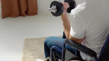 Tekerlekli sandalyedeki engelli sporcu, halterlerle, evde eğitimle ve fiziksel aktiviteyle egzersiz yapıyor