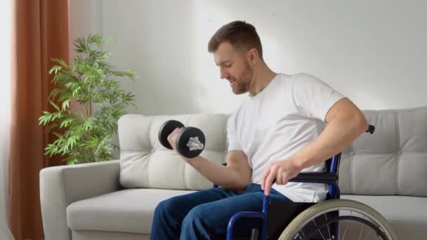 Atleta discapacitado en silla de ruedas realiza ejercicios con pesas, entrenamiento en casa y actividad física — Vídeos de Stock