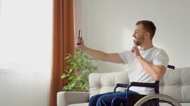 Persona discapacitada feliz sentada en una silla de ruedas y tomando una selfie. La vida de una persona con discapacidad — Vídeo de stock