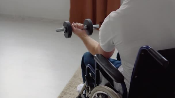 Behinderter Sportler im Rollstuhl macht Übungen mit Kurzhanteln, Heimtraining und körperlicher Aktivität — Stockvideo