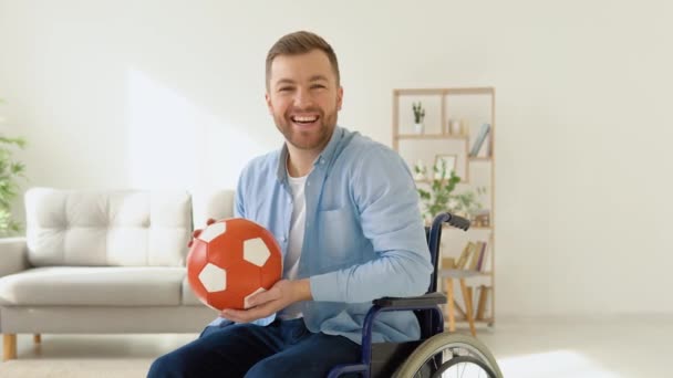 Yürümeden önce elinde kırmızı bir topla tekerlekli sandalyede oturan mutlu bir sakat. — Stok video