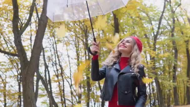 아름다운 금발의 여자가 잎으로 우산을 들고 내려오는 모습 — 비디오