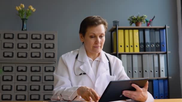 Médico senior femenino hacer videollamada en línea consultar paciente — Vídeos de Stock